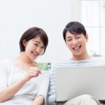 JCBカードをかざしながらパソコンを見る女性と男性