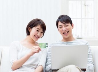 JCBカードをかざしながらパソコンを見る女性と男性