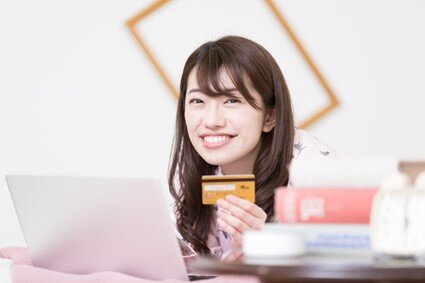 クレジットカードを手に取って微笑む女性